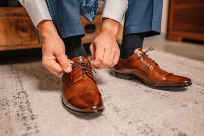 Groom in black tuxedo and bowtie correct his buttons on white shirt. Wedding. Details